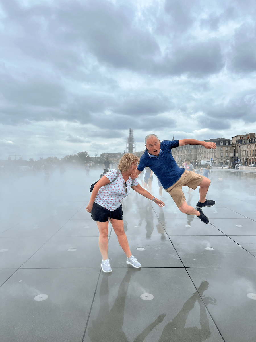 Una pareja de turistas disfruta en el Espejo del Agua, en la plaza de la Bolsa, Burdeos (Francia)