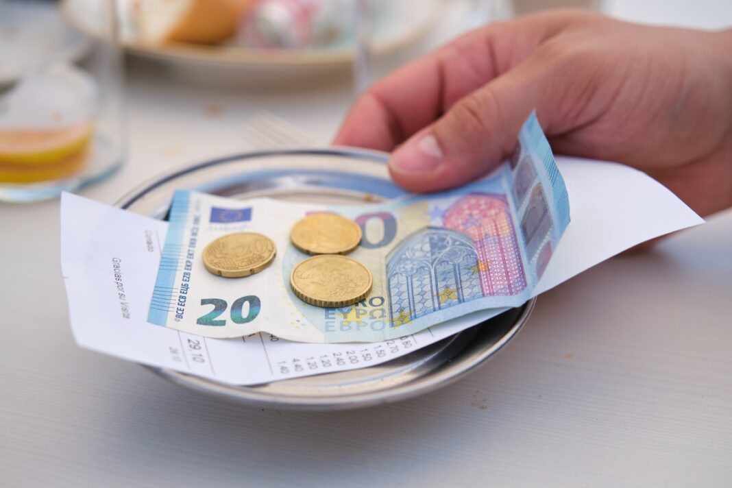 Hand bringing back the metal bill tray with the change. Las propinas son un gesto valorado como buen hábito entre los restaurantes