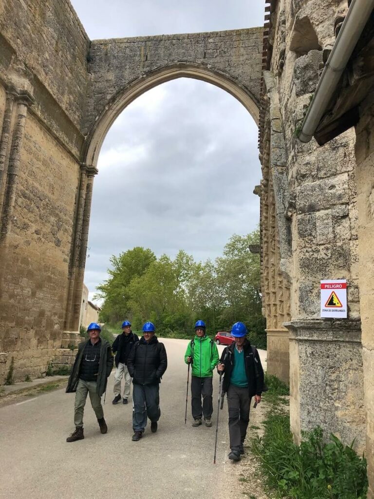 Peregrinos con casco protector a su paso por el tramo de los arcos de las ruinas del convento de San Antón, en Castrojeriz, Burgos